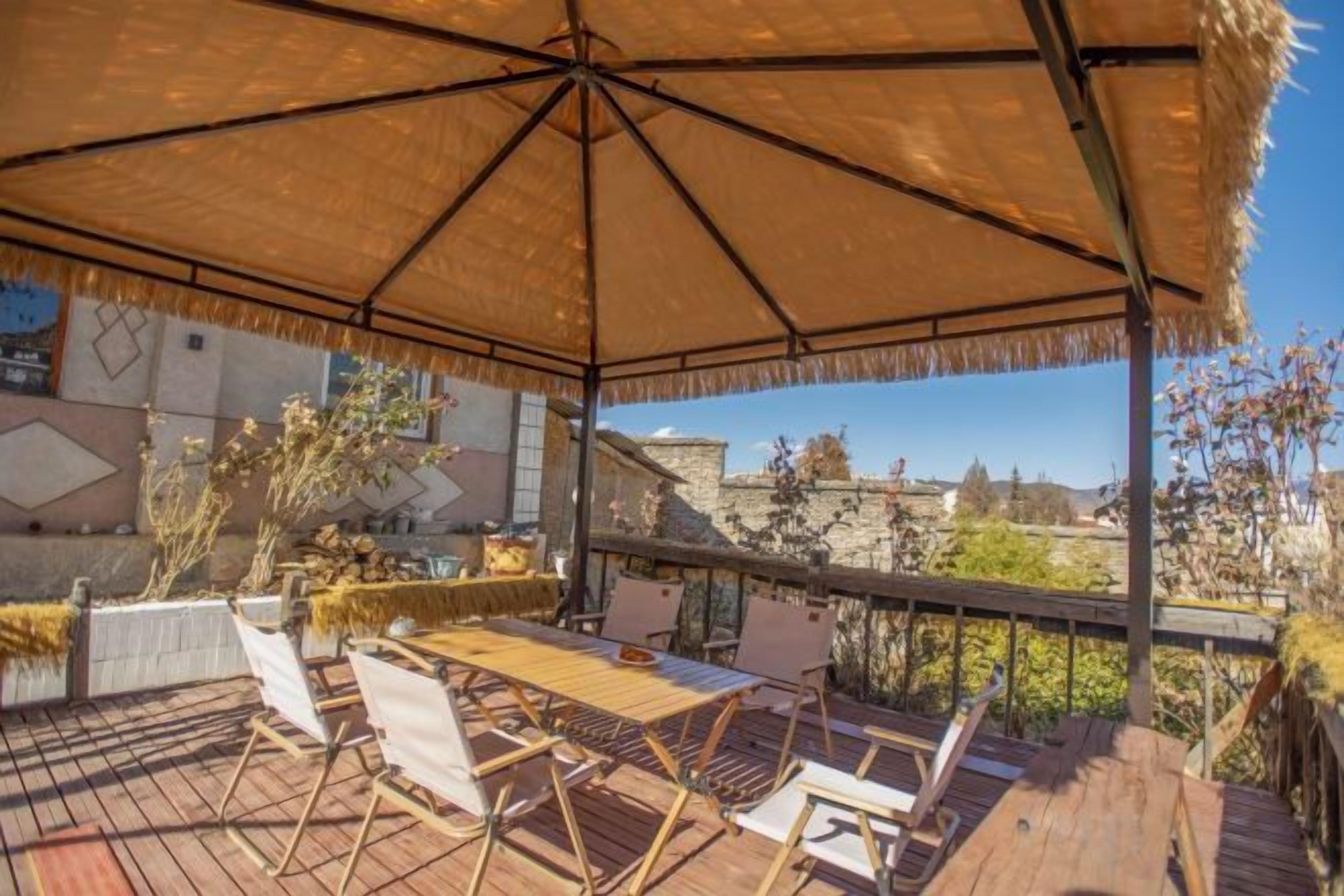 An outdoor patio with a thatched umbrella, wooden deck, and lounge chairs.