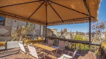 An outdoor patio with a thatched umbrella, wooden deck, and lounge chairs.