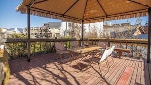 A covered outdoor seating area with a table and chairs, overlooking a scenic landscape. - Cozy Mountain Inn (Shangri-La)