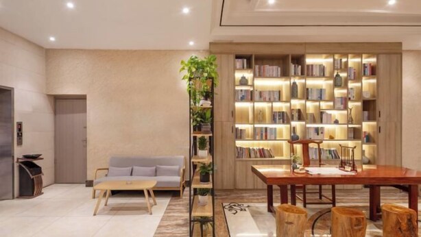 A modern living room with a sofa, coffee table, wooden bookshelf, and a dining table. - Hua Ju Hotel (Subway Station, Duduanqiao, Mudu Town, Suzhou) (Suzhou)