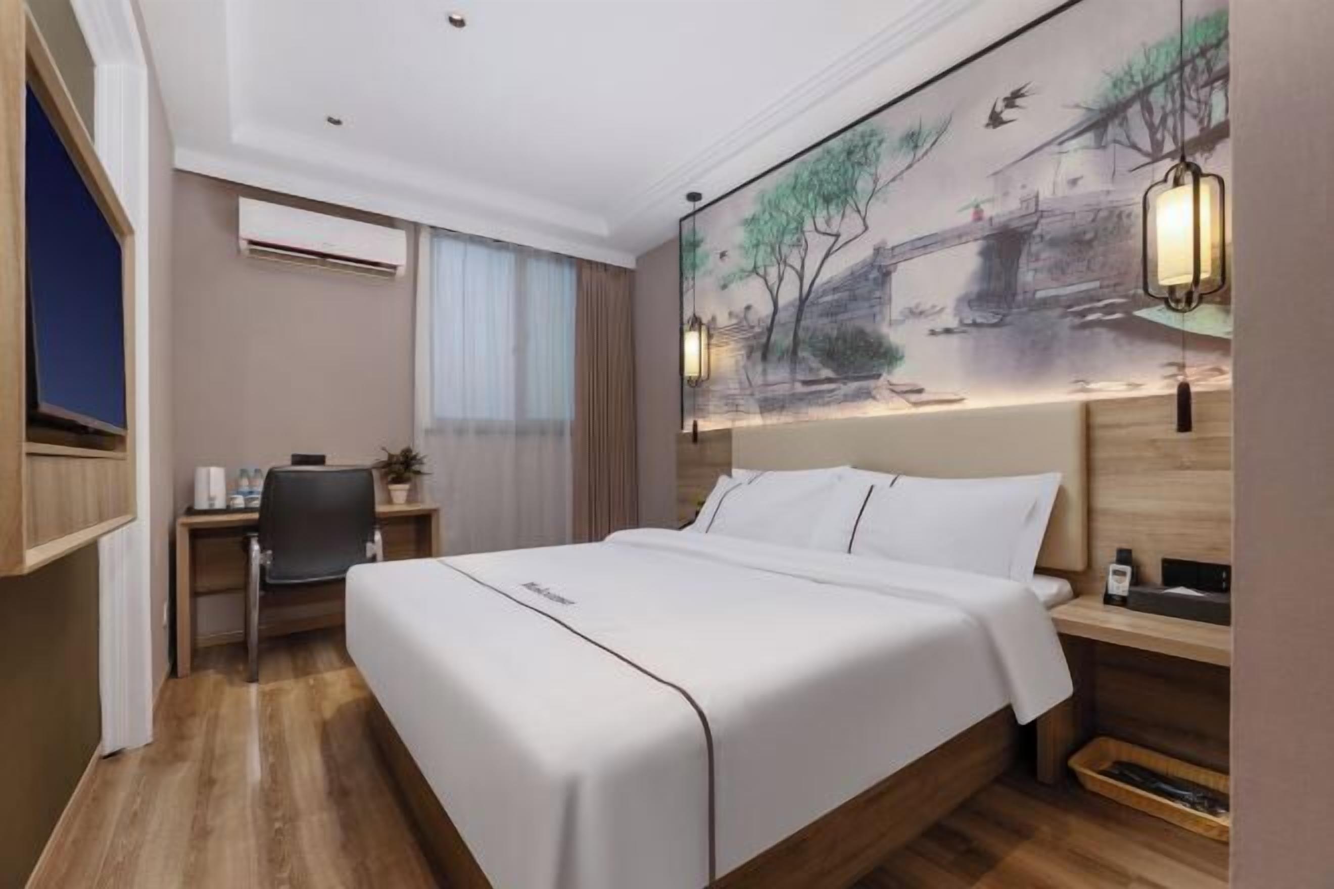 Ein Hotelzimmer mit Bett, Schreibtisch, Stuhl und einem Bild an der Wand.