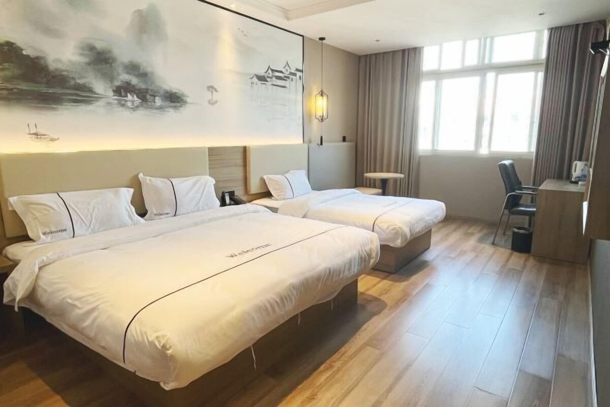 A hotel room with two beds, a desk, and a chair.