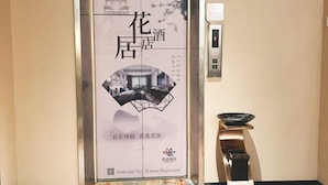 A hotel elevator with a poster featuring traditional Chinese architecture and a modern interior. - Hua Ju Hotel (Subway Station, Duduanqiao, Mudu Town, Suzhou) (Suzhou)