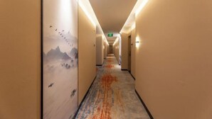 A hotel hallway with a carpet featuring a mountain landscape and birds. - Hua Ju Hotel (Subway Station, Duduanqiao, Mudu Town, Suzhou) (Suzhou)