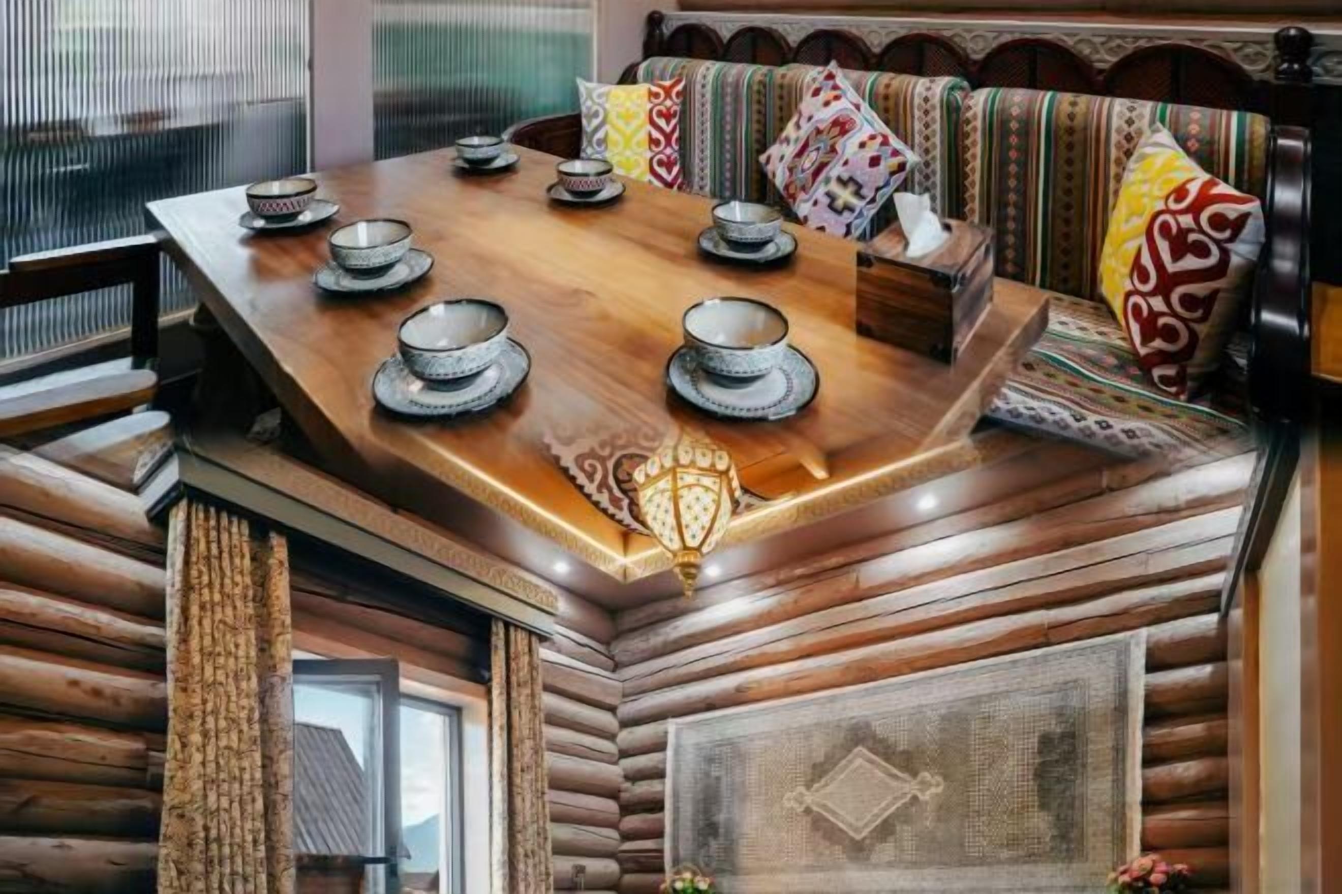 Una mesa de madera para comer con cuencos y platos, un sofá estampado y un adorno en la pared.