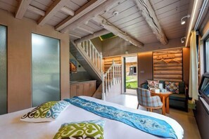 Une chambre d’hôtel avec un lit, un escalier, un petit coin repas et une vue sur l’extérieur.