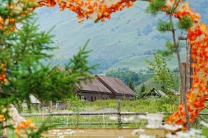 Un graner de fusta rústic en un paratge rural amb les verdes muntanyes al fons.