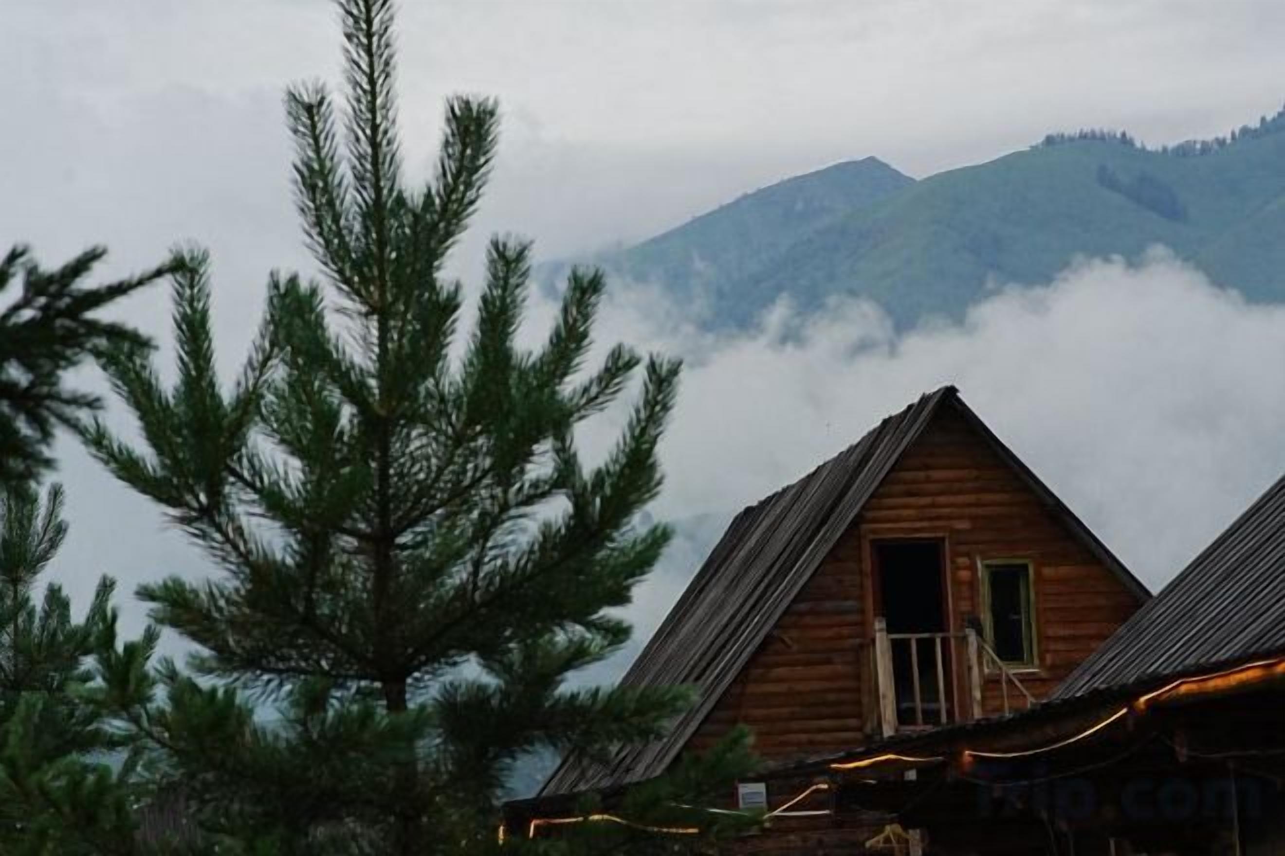 Une cabane en bois avec une entrée bien visible et une montagne en arrière-plan.