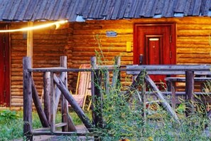 A rustic wooden cabin with a porch, a red door, and a sign above the door. - Hemu Free Tribe Villa (Burqin)