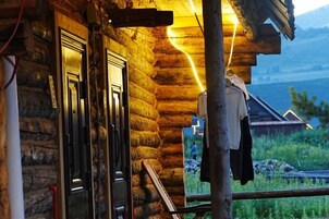 Una cabaña de troncos con puerta de madera y abrigo colgado en el exterior.
