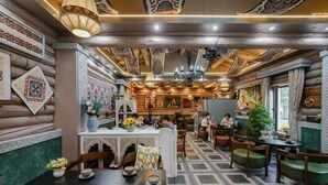 A cozy restaurant with wooden walls, patterned ceiling, and a central dining area with tables and chairs. - Hemu Free Tribe Villa (Burqin)