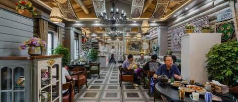 A restaurant with a patterned floor, wooden ceiling, and tables with chairs.