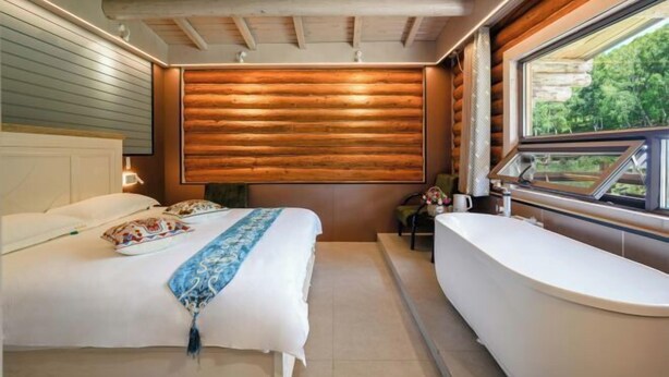 A bedroom with a bed, a window, and a bathtub. - Hemu Free Tribe Villa (Burqin)