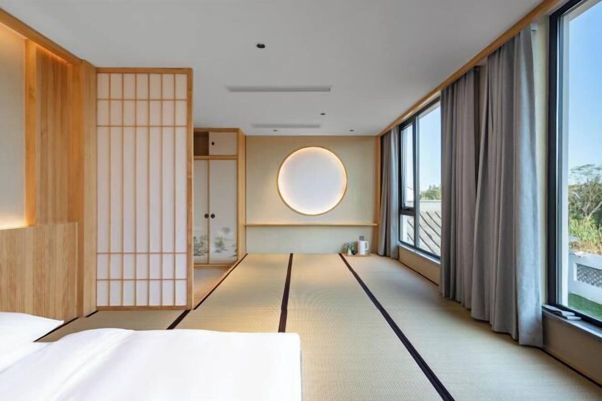 A traditional Japanese-style room with tatami flooring, a shoji screen, and a circular wall light.