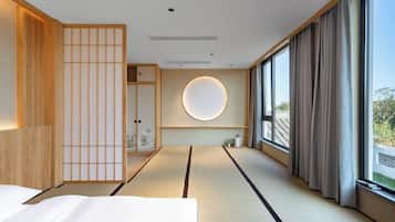A traditional Japanese-style room with tatami flooring, a shoji screen, and a circular wall light.