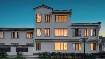 A multi-story residential building with a symmetrical facade, large windows, and a well-maintained lawn.