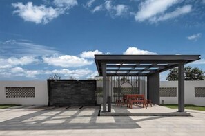 An outdoor patio with a pergola, seating, and a gate.