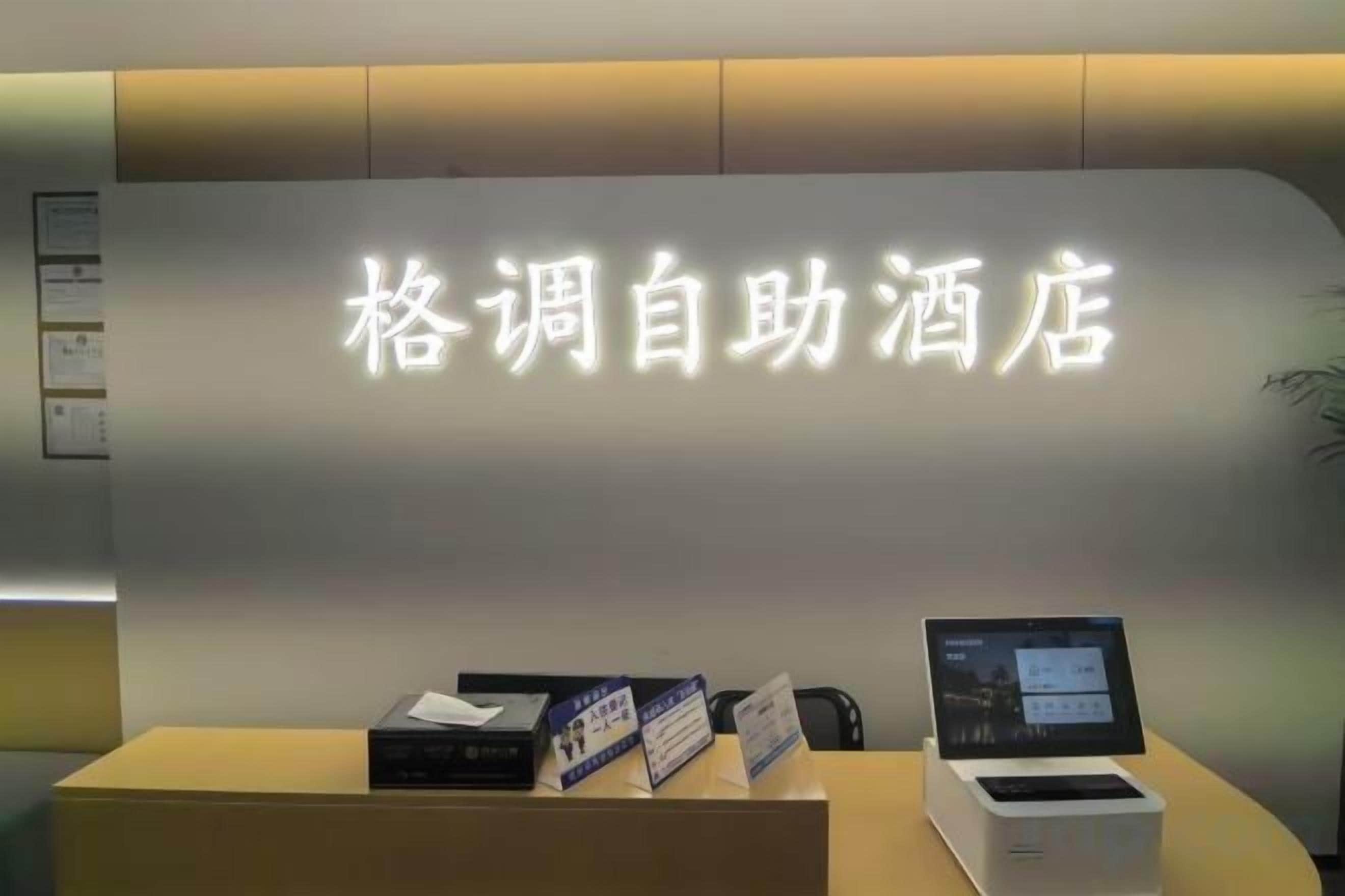 A reception desk with a sign in Chinese characters, a computer, and a small display screen.