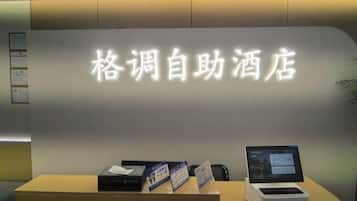 A reception desk with a sign in Chinese characters, a computer, and a small display screen.