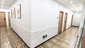 Ein Korridor mit weißen Wänden, Holztüren und einem gemusterten Boden.