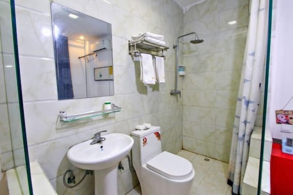 A bathroom with a sink, toilet, and shower. There is a glass shelf above the sink and a towel rack with towels. - Style Theme Hotel (Fuyang Normal University West Lake Campus) (Fuyang)