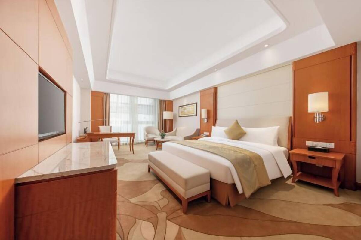 Una habitación de hotel moderna con una cama grande, un escritorio, una silla y un televisor.