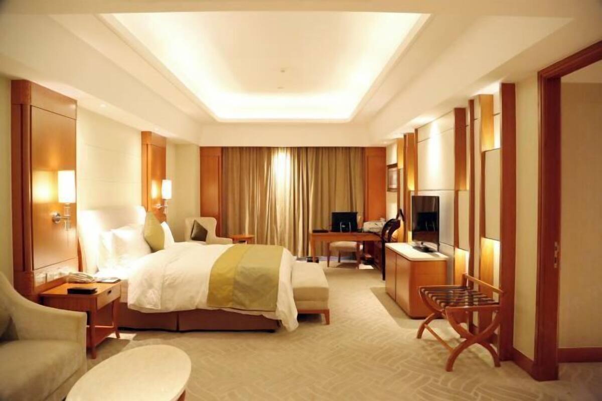 Habitación de hotel con cama, escritorio, silla y televisor.