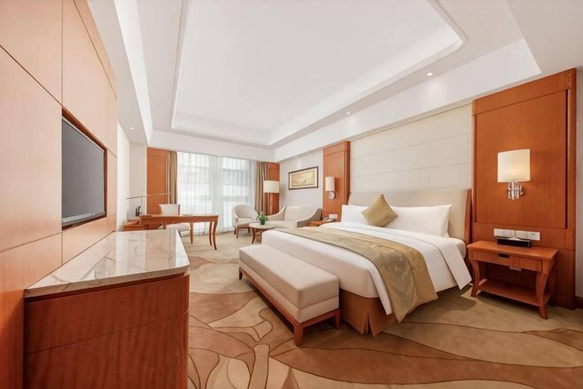 Una habitación de hotel con una cama grande, un escritorio, un televisor y una zona de estar.