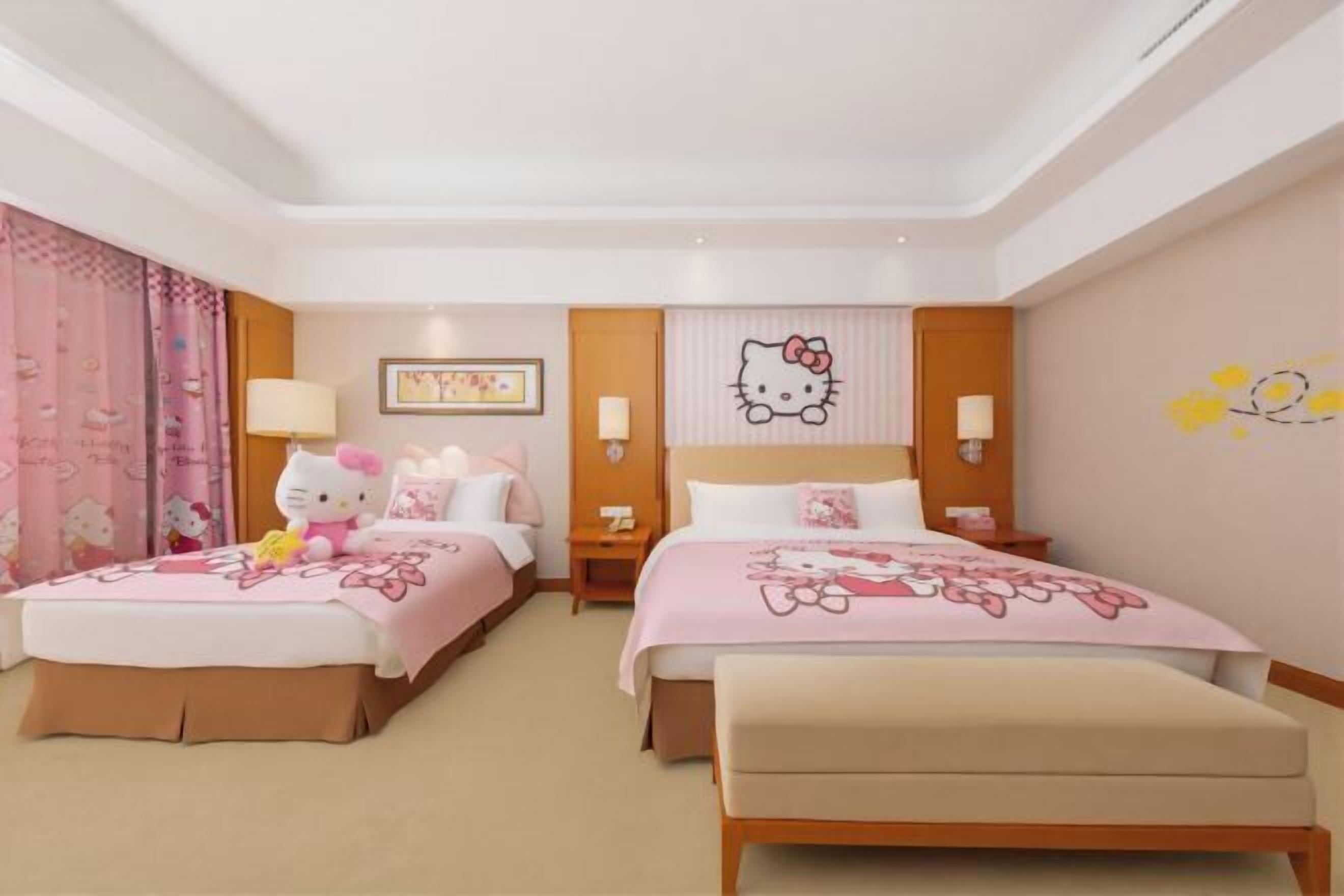 Habitación de hotel con dos camas, un banco, un adorno de pared de Hello Kitty y un cuadro enmarcado.