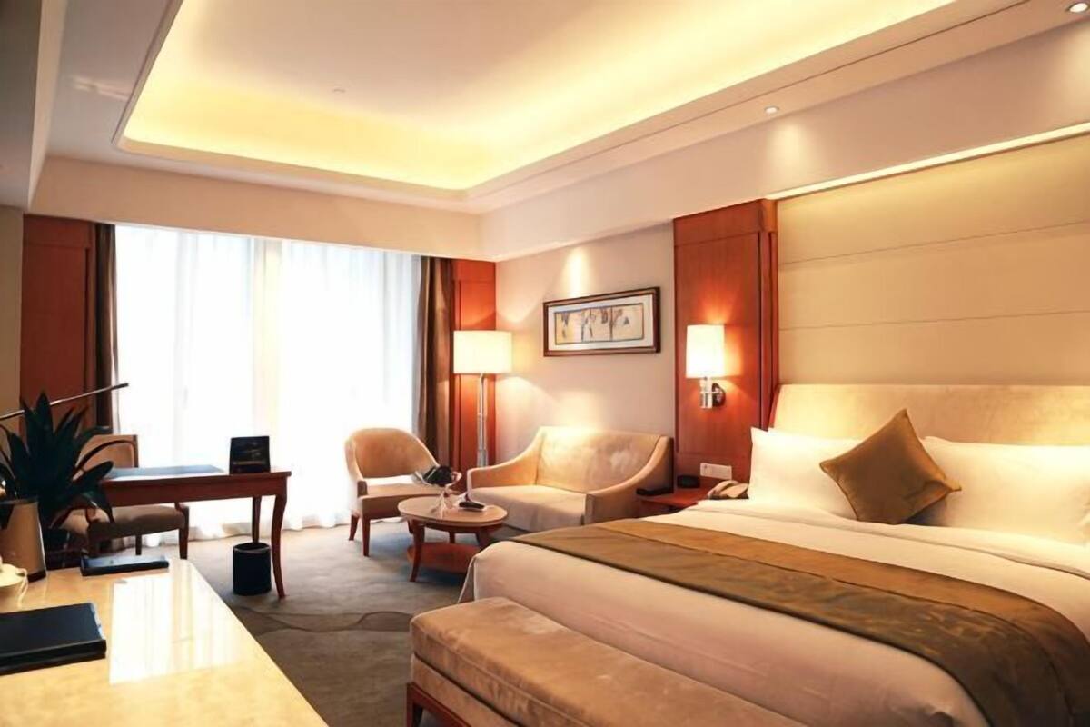 Una habitación de hotel con una cama grande, dos sillones, un escritorio y una lámpara.