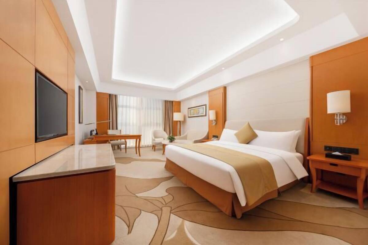 Una habitación de hotel con una cama grande, un escritorio, una silla y un televisor.