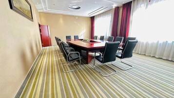 A conference room with a long table, chairs, and a striped carpet.