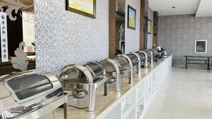A buffet setup with multiple food dispensers, a marble counter, patterned walls, and a bench in a well-lit room. - Fuyuan Yayue Business Hotel (Fuyuan)