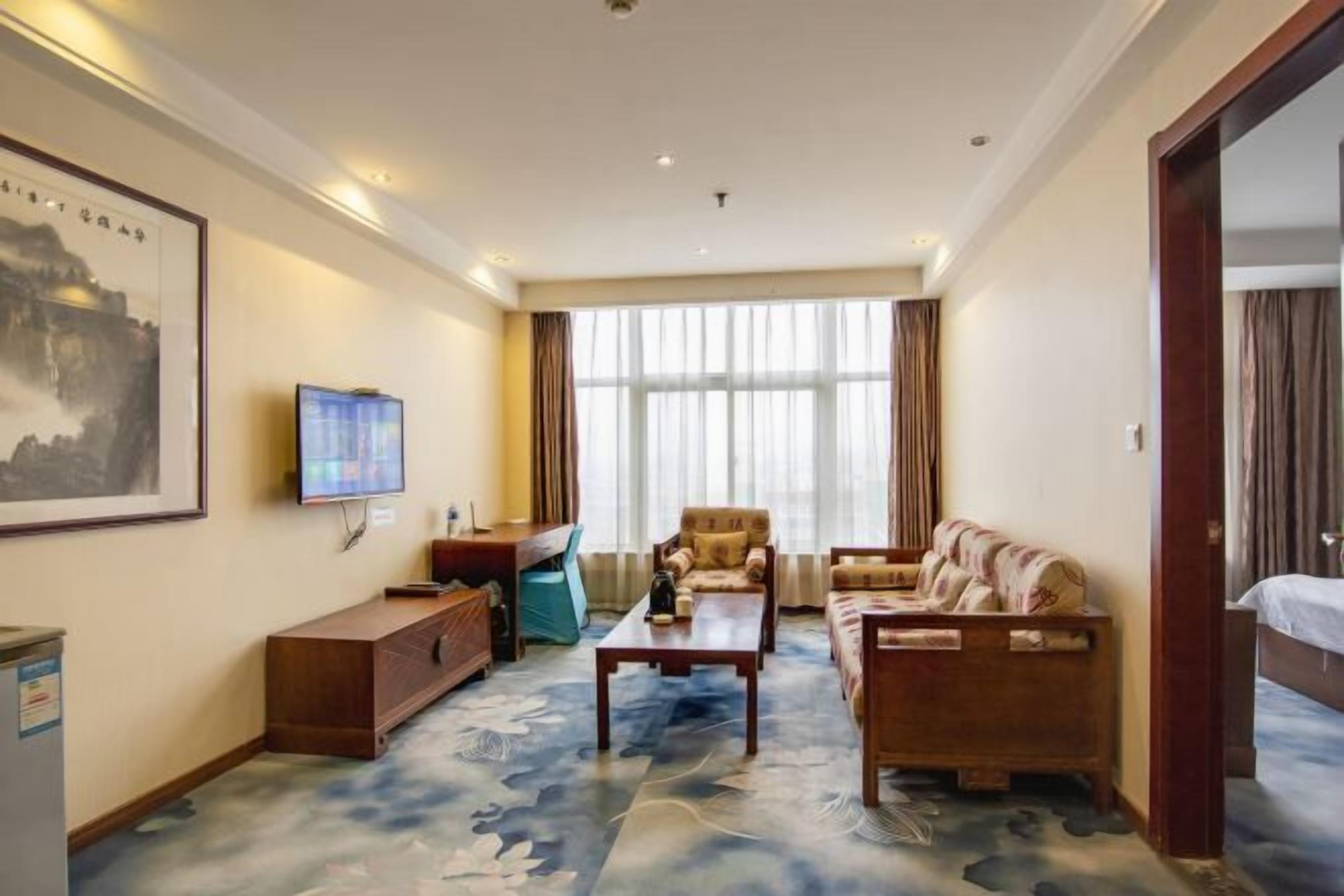 Une chambre d’hôtel équipée d’un canapé, d’un fauteuil et d’un bureau avec une télévision.