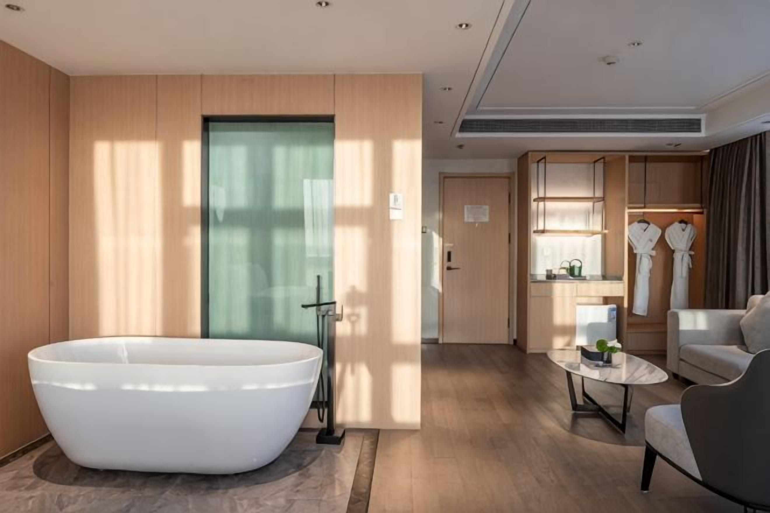 A modern bathroom with a freestanding bathtub, a shower area, and a seating area with a coffee table.