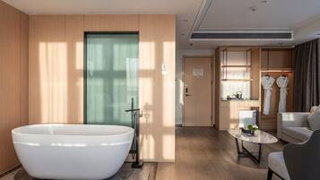 A modern bathroom with a freestanding bathtub, a shower area, and a seating area with a coffee table.