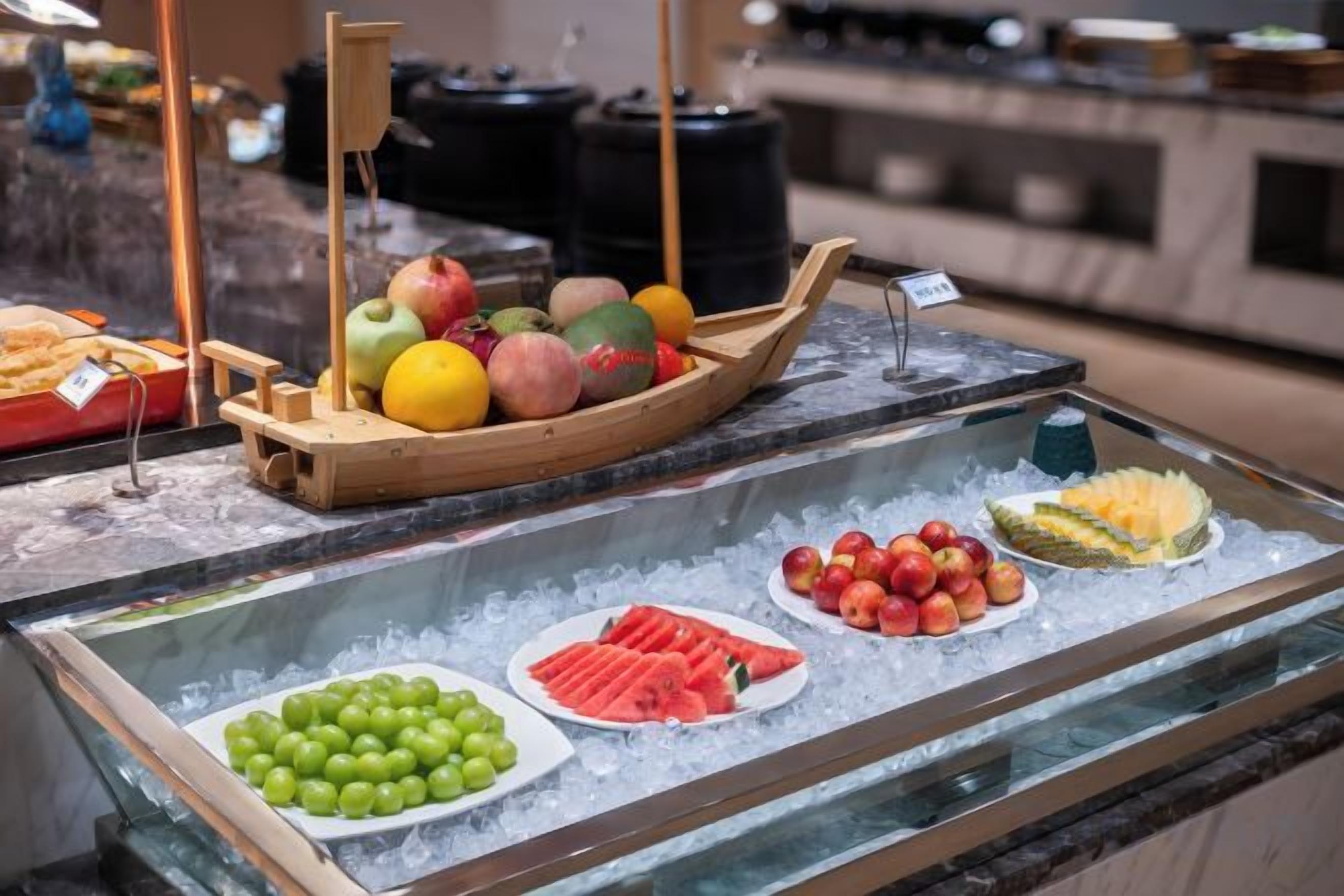 A fruit display with a wooden boat and ice.
