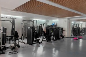 A gym with various exercise equipment, including weight machines and free weights. - Madison Hotel Qingdao City Center (May Fourth Square) (Qingdao)