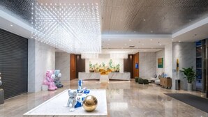 A modern lobby with a reception desk, seating area, and decorative sculptures.