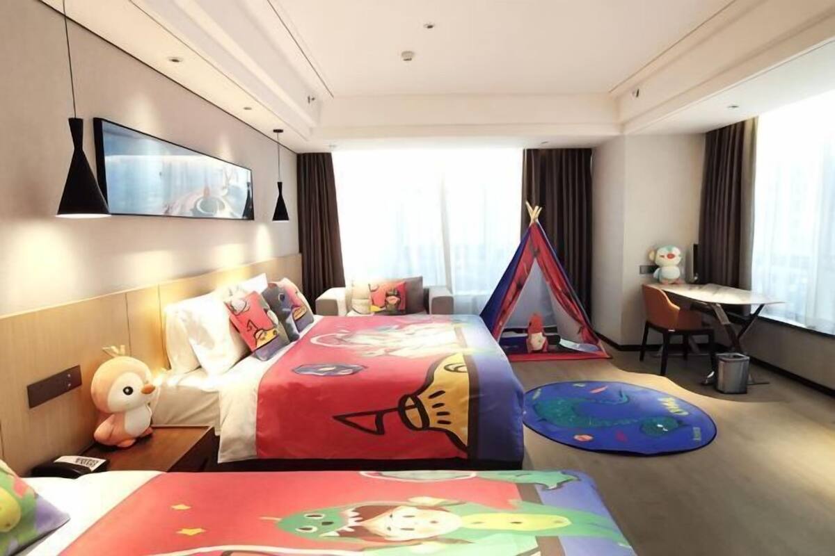 Ein Hotelzimmer mit Bett, Schreibtisch, Stuhl, Fernseher und Fenster.