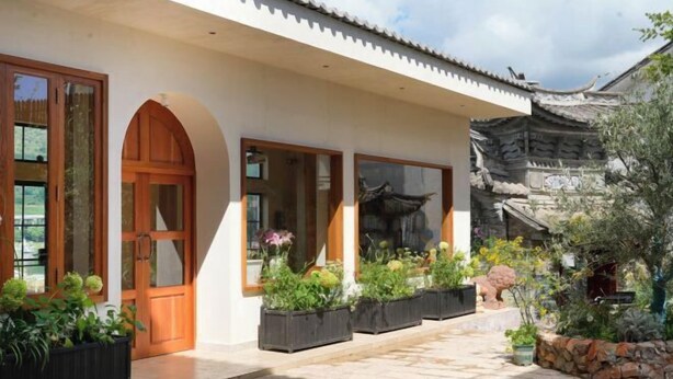 A traditional building with large wooden doors and windows, a tiled walkway, and potted plants. - Dali Nuan Nuan Ying Jing Cliff Sea View Hotel (Dali City)