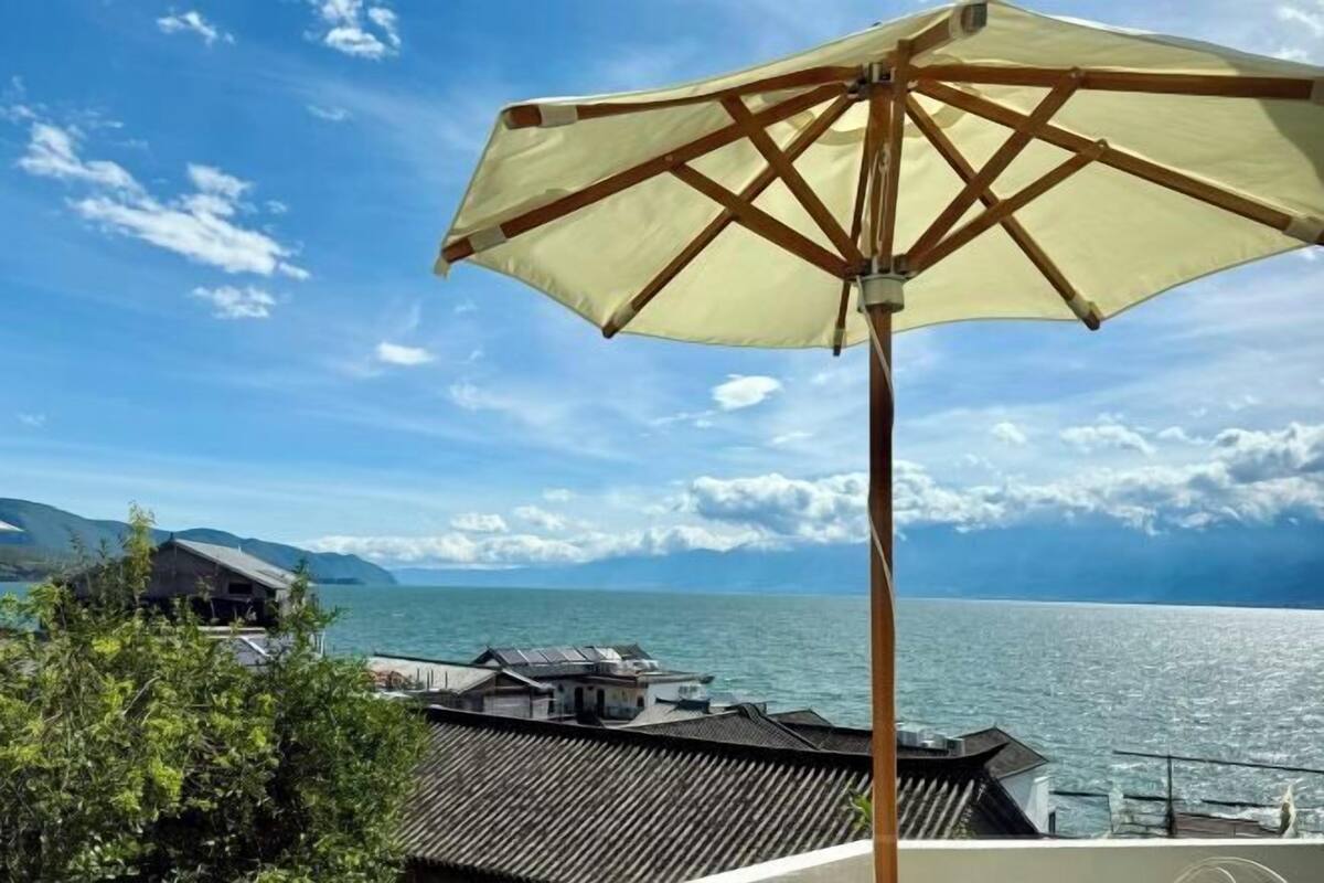A wooden umbrella, a view of the sea, and a building with a sloped roof.
