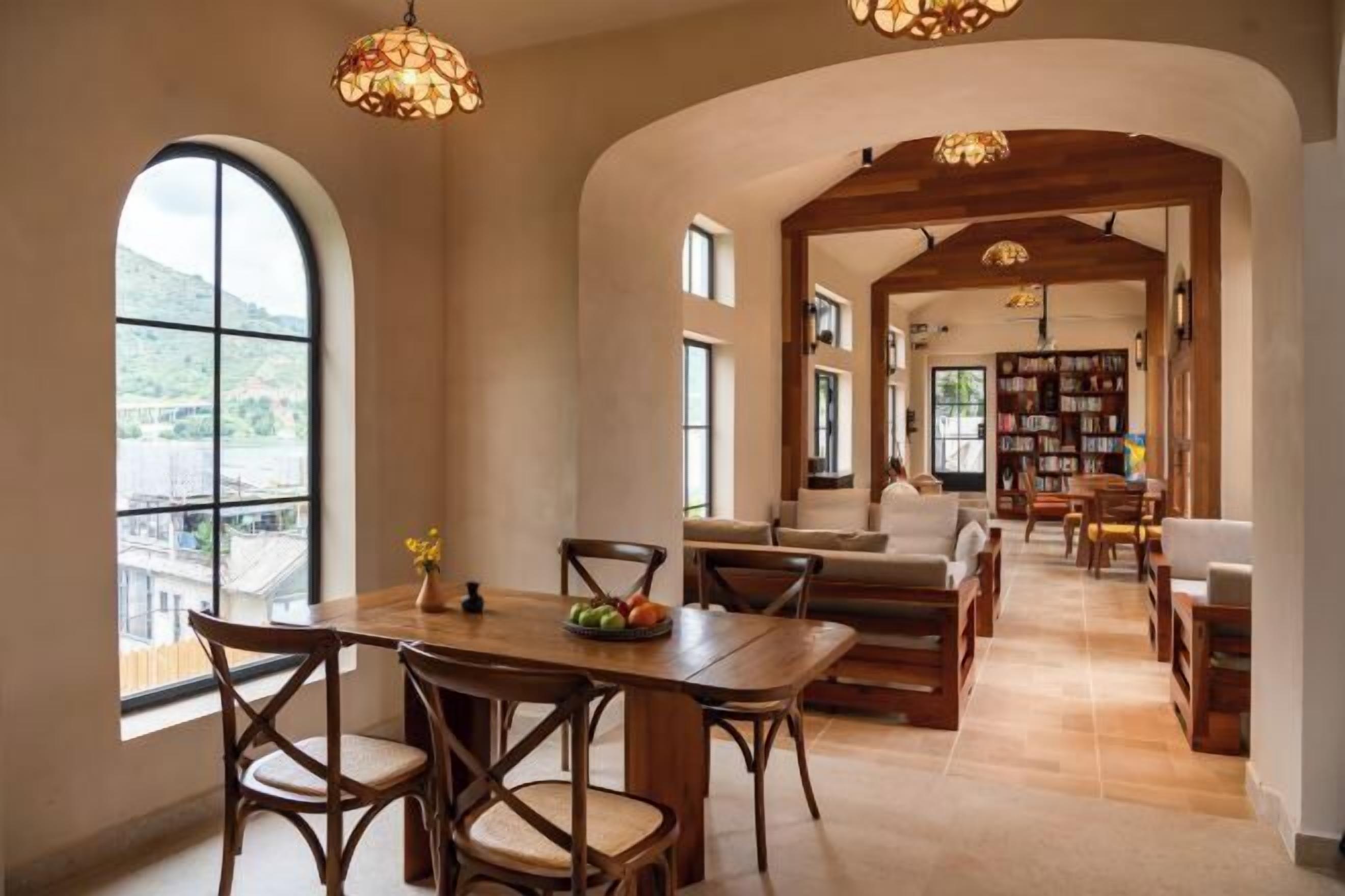 A spacious living area with a wooden dining table, comfortable seating, and a bookshelf.