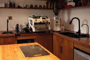 Una cocina con cafetera, lavamanos y encimera de madera.
