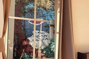 A glass door with a view of a room featuring a large, colorful mural on the wall.