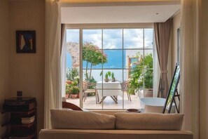 A room with a large window, a sofa, a table, and chairs.