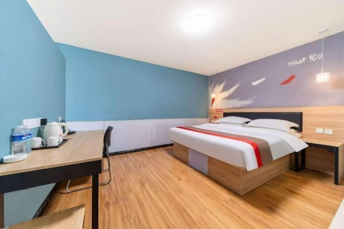 Una habitación de hotel moderna con cama, mesita de noche y escritorio con silla.