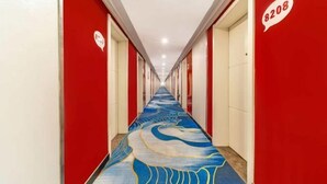 A hotel hallway with red walls and a blue carpet featuring a wave pattern. - Shankee Hotel (Linyi Baishabu) (Linyi)