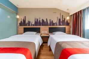 A hotel room with two beds, a cityscape mural on the wall, a wooden headboard, and a nightstand with a lamp. - Shankee Hotel (Linyi Baishabu) (Linyi)