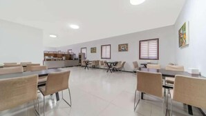 A spacious dining area with multiple tables and chairs, a kitchen area in the background, and artwork on the walls. - Shankee Hotel (Linyi Baishabu) (Linyi)